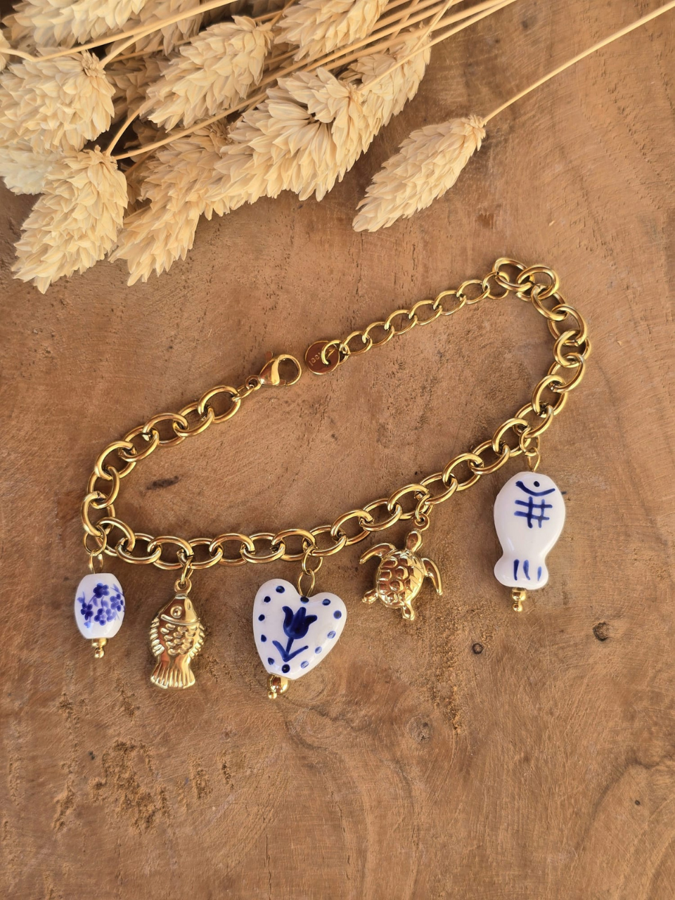 Bracelet breloques en acier inoxydable doré avec perles bleues et blanches.