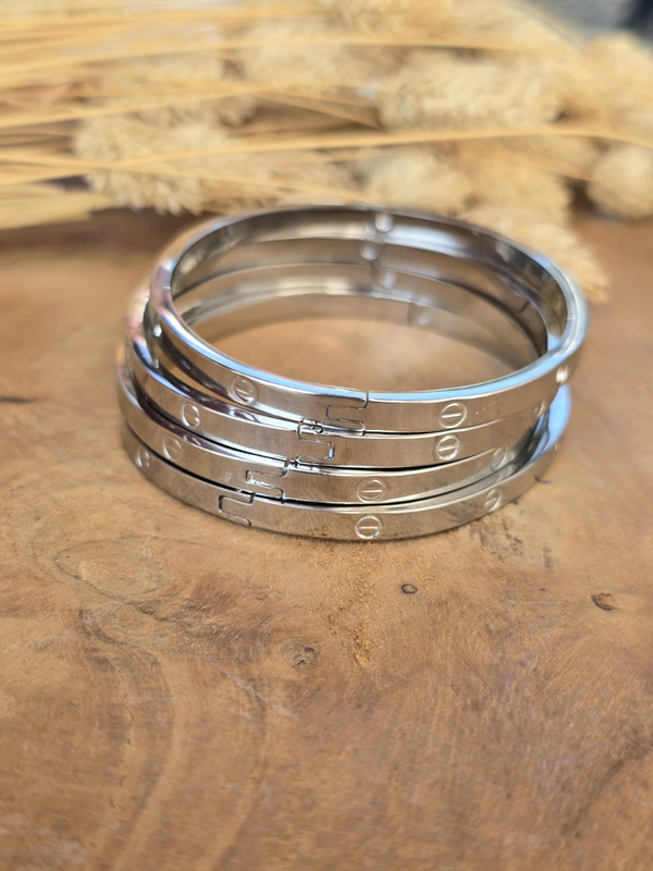 Bracelet jonc rigide argenté en acier inoxydable avec gravures décoratives.