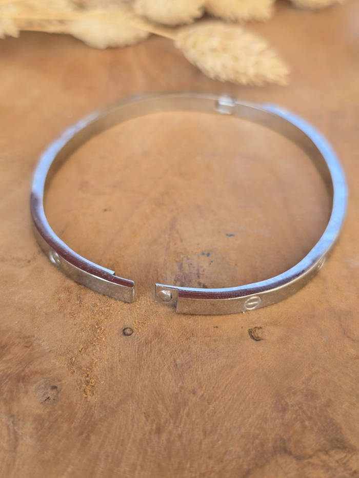 Bracelet jonc rigide argenté en acier inoxydable avec gravures décoratives.