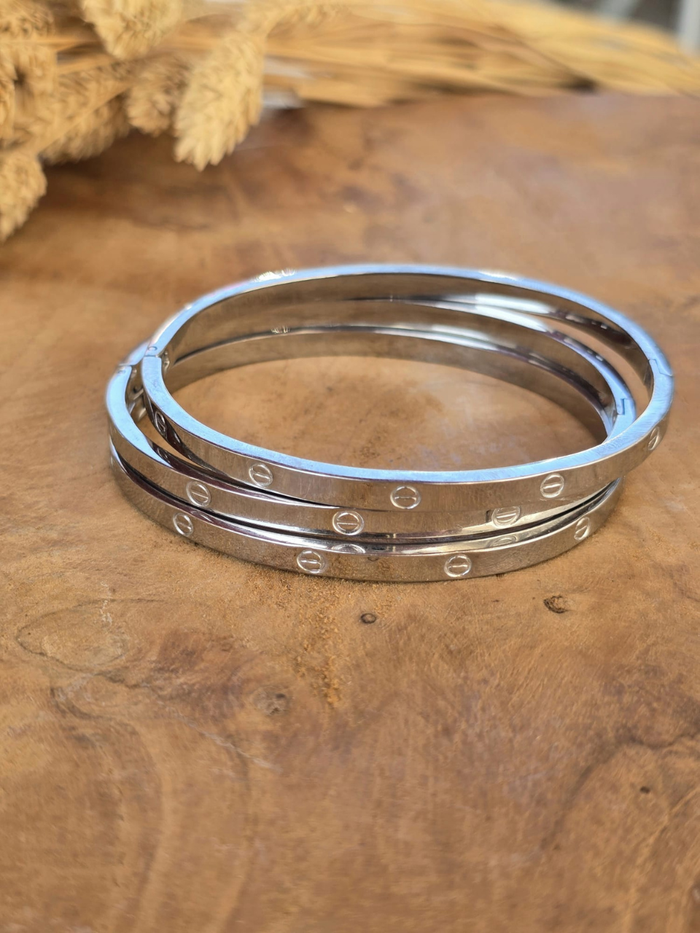 Bracelet jonc rigide argenté en acier inoxydable avec gravures décoratives.