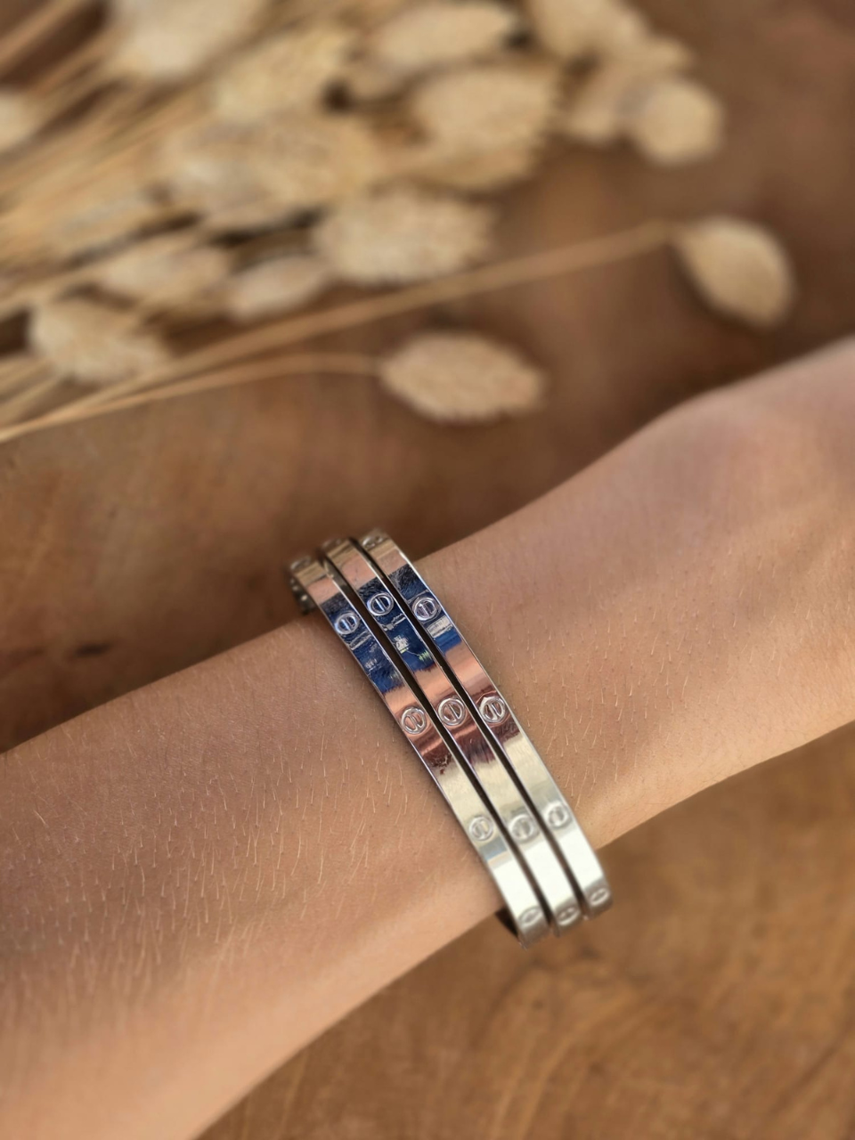 Bracelet jonc rigide argenté en acier inoxydable avec gravures décoratives.