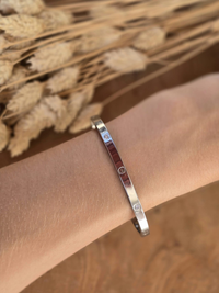 Bracelet jonc rigide argenté en acier inoxydable avec gravures décoratives.