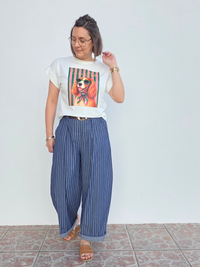 Tee-shirt blanc original femme avec imprimé chien porté avec pantalon rayé bleu.