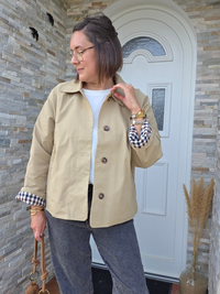 Trench court femme beige à revers carreaux porté manches retroussées